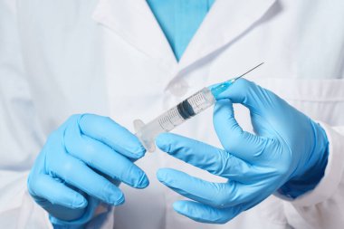 Doktor elinde aşı ya da ilaç gibi bir şeyle şırınga tutuyor.