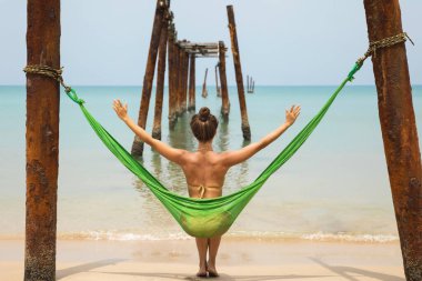 Genç kadın hamakta dinleniyor kırık iskeleden sarkan eski kirişlere asılı.