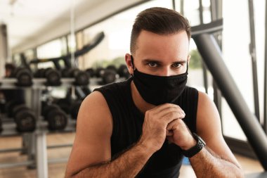 Yeni normal konsept. Spor salonundaki antrenmanı sırasında koruyucu yüz maskesi takan genç bir atletik..