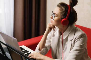 Düşünceli kadın besteci ev stüdyosunda müzik yazıyor.