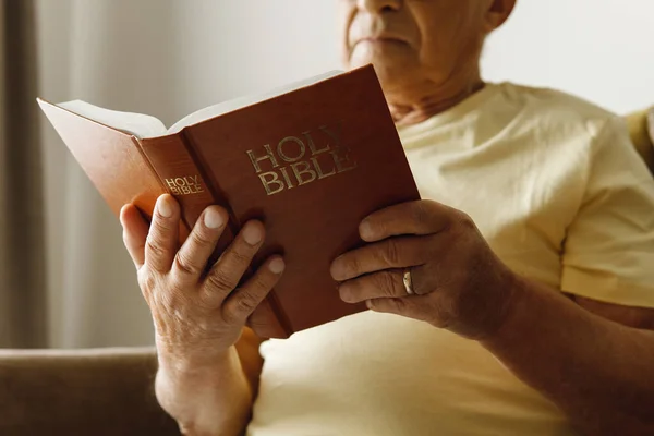 Elderly man reading holy bible at home