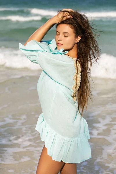 美しい青いドレスを着た若い素敵な女性が海辺を歩いています — ストック写真