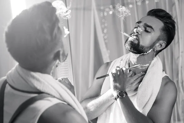 英俊的男人看着镜子 刮胡子 用一把直的剃须刀 — 图库照片