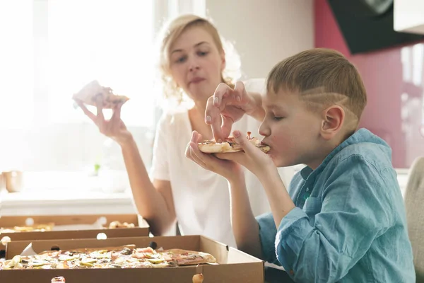妈妈和她可爱的儿子在家里吃美味的意大利披萨 — 图库照片
