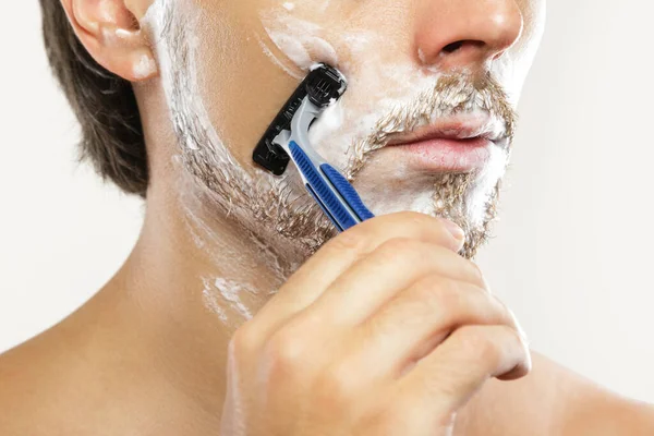 安全剃刀で顔にクリームを剃る若い男 — ストック写真