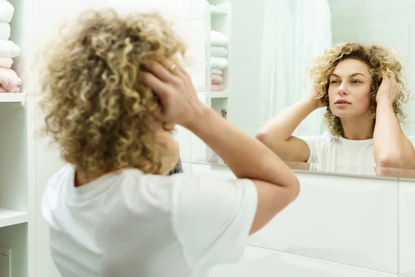Genç Güzel Bir Kadın Kıvırcık Saçlı Banyoda Aynaya Bakıyor — Stok fotoğraf