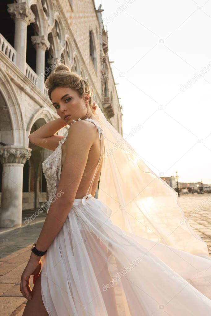 Portrait of young woman wearing beautiful white dress walking on a street of the Venice city