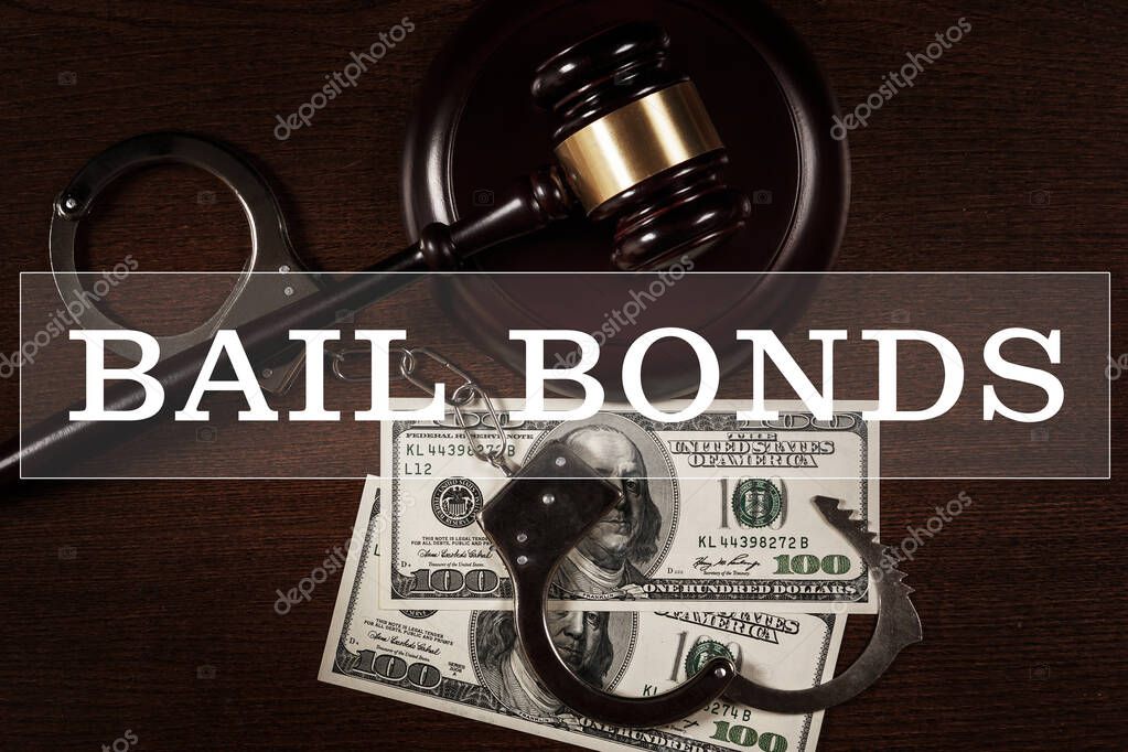 Bail bonds services concept. Judge gavel, handcuffs and money on wooden background.