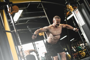 Vücut geliştirici spor salonunda çalışırken göğüs için kablo çapraz egzersizi yapıyor.