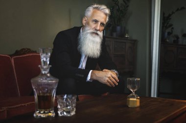 Şık ve yakışıklı sakallı adam viski içiyor.