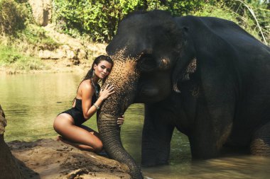 Mutlu genç kadın nehirde fille banyo yapıyor.