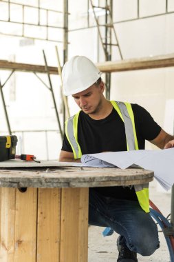 Young, inşaat sahasının planları üzerinde çalışıyor.