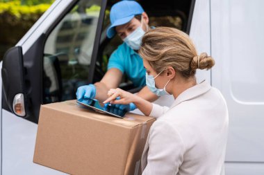 Önleme maskeleri yeni güvenlik önlemleri. Karavandaki teslimatçıdan paket alan genç bir kadın.