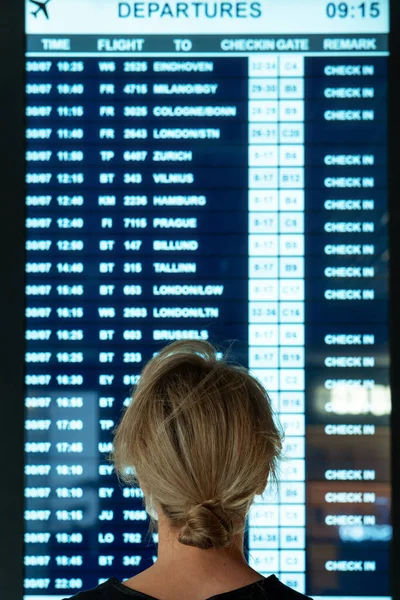 空港でのフライトに関する情報を表示している若い女性 — ストック写真
