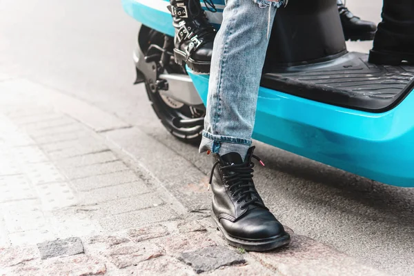 Couple riding motorcycle. Close-up of a scooter body and legs wearing boots