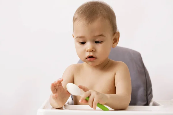 用勺子坐在高椅子上的可爱的饥饿的婴儿 — 图库照片