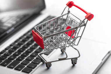 Dizüstü bilgisayarın klavyesinde minyatür alışveriş arabası. Online alışveriş ve e-ticaret kavramı.