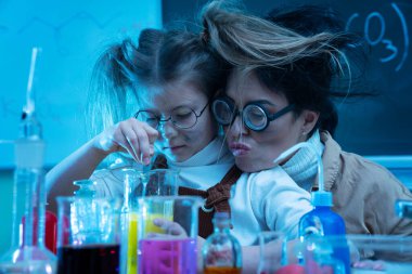Kimya dersi sırasında laboratuvarda kimyasalları karıştıran komik öğretmen ve küçük kız.