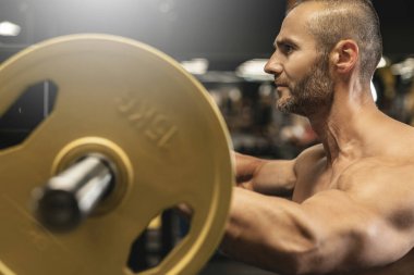 Spor salonunda halterle çalışırken sakallı yakışıklı bir vücut geliştirici.