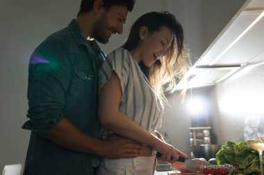 Genç bir çift akşam mutfakta lezzetli yemekler pişiriyor.