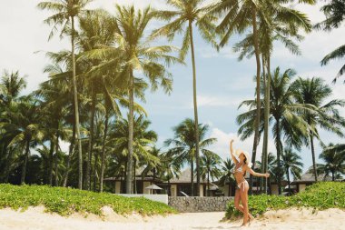 Güzel ve mutlu bir kadın plajda palmiye ağaçlarıyla