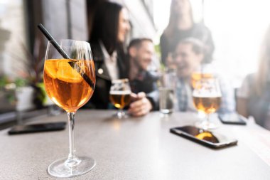 Arka planda oturan bir arkadaş grubuyla masada Aperol Spritz kokteyli.
