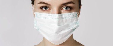 Genç beyaz kadın virüse karşı korunmak için maske takıyor.