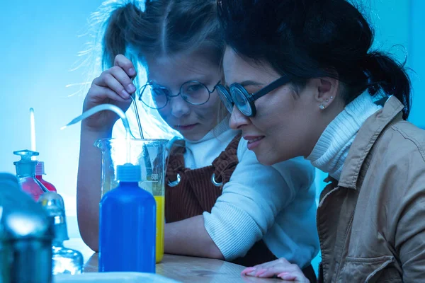 Funny teacher and little girl during chemistry lesson mixing chemicals in a laboratory