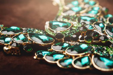 Kahverengi kadife arka planda yeşil değerli taşlar olan lüks bir kolye.