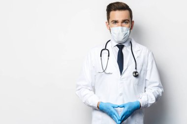 Steteskoplu kendine güvenen doktor koruyucu maske ve lateks eldiven takıyor.