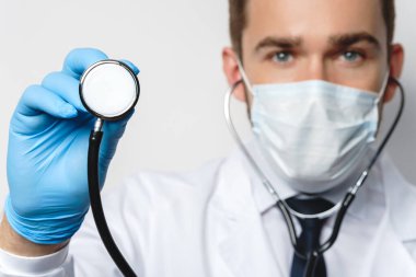 Steteskoplu kendine güvenen doktor koruyucu maske ve lateks eldiven takıyor.