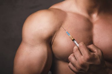 Elinde şırıngayla kaslı bir adam. Güç egzersizi ve anabolik steroid kullanımı kavramı.