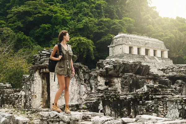 Hiker woman with a backpack looking at ancient Mayan ruins