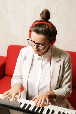 Evde sentezleyici çalan genç ve güzel bir kadın.