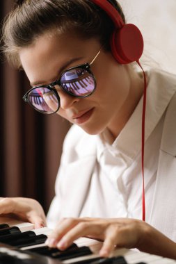 Genç kadın besteci portresi. Gözlüklü piyano tuşlarının yansıması.