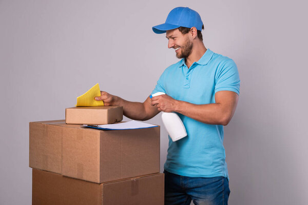 Happy delivery man during work with a packages in a cardboard boxes over gray background