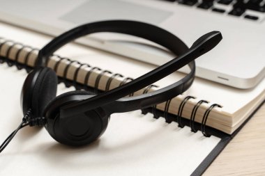 Açık bir deftere takılmış siyah bir kulaklığın yakın çekimi.