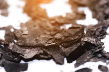 Beyaz arka plana yanmış kül ve enkaz parçaları serpiştirilmiş..