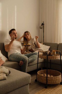 Bir çift sıcak lving odasında patates kızartması ve tavuk nugget paylaşıyor..