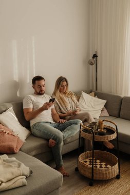 Smartphone kullanarak ve kahve içerek birlikte oturan mutlu çift..