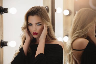 Kırmızı dudaklı, güzel saçlı, gösterişli ışıklarla poz veren çarpıcı bir kadın..