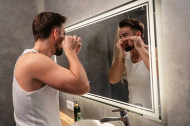 Banyodaki aynanın önünde göz bandı altında başvuran bir adam..