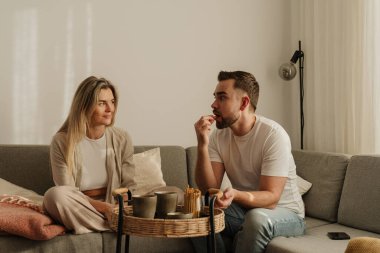 Çift Evde Kanepede Atıştırmalık ve Sohbetin Tadını Çıkartıyor.