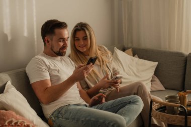 Smartphone kullanarak ve kahve içerek birlikte oturan mutlu çift..