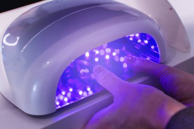 Jel manikür tedavisinde müşterinin elleri mor ötesi lambanın altında..