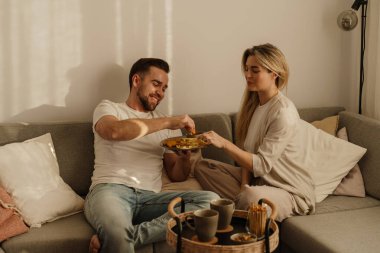 Bir çift sıcak lving odasında patates kızartması ve tavuk nugget paylaşıyor..