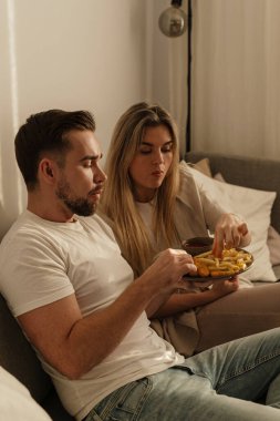 Bir çift sıcak lving odasında patates kızartması ve tavuk nugget paylaşıyor..