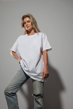 Büyük boy beyaz tişört giyen kendine güvenen bir kadın. Model için boş yeri var..