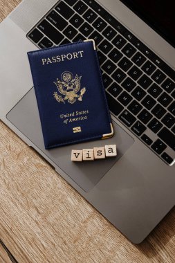 ABD pasaportu, dizüstü bilgisayarda VISA 'yı heceleyen tahta bloklarla seyahat izni ve göçmenlik kavramını sembolize ediyor..