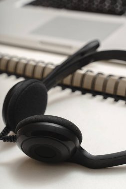 Açık bir deftere takılmış siyah bir kulaklığın yakın çekimi.